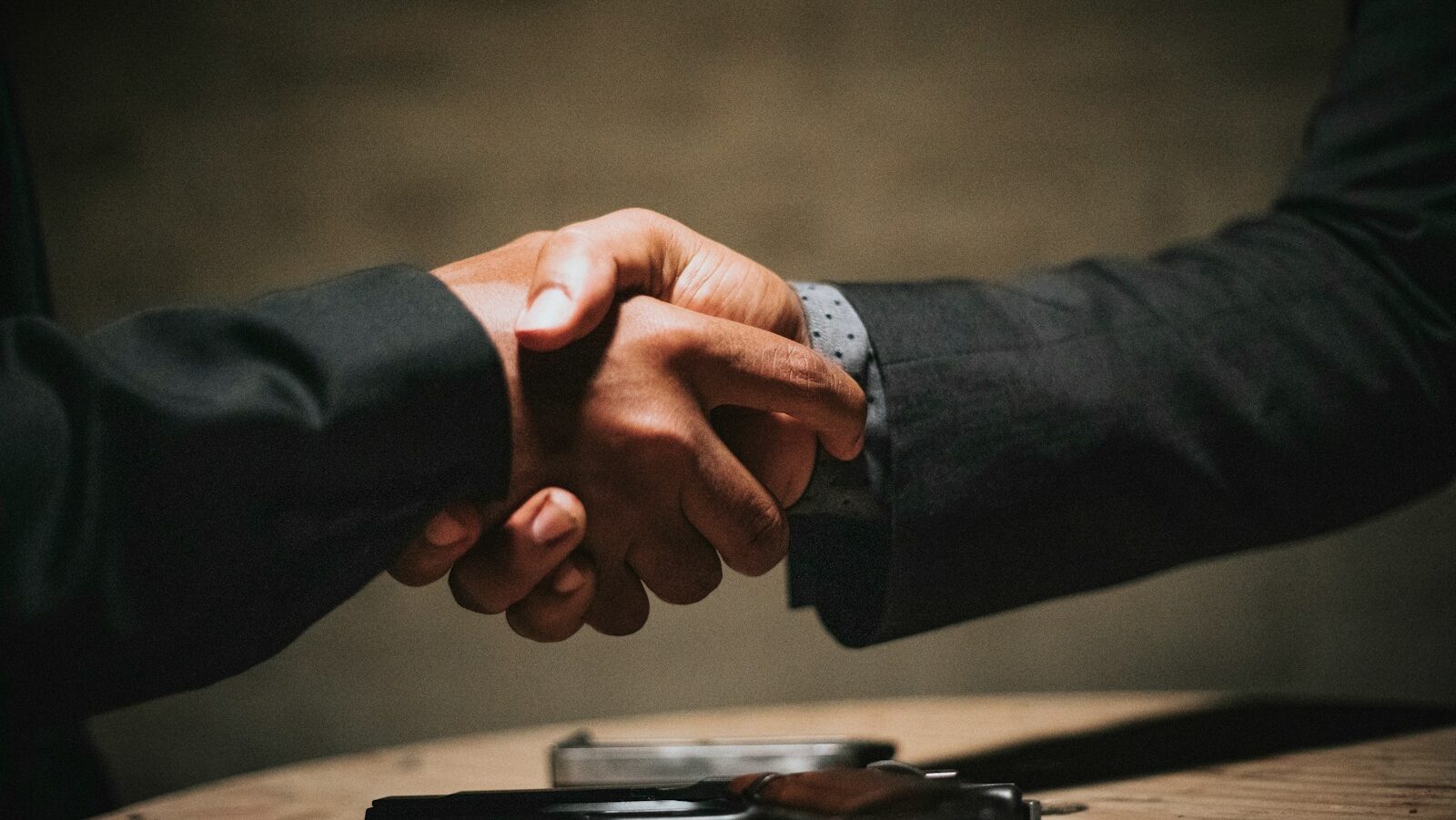 two people shaking hands over a wooden table